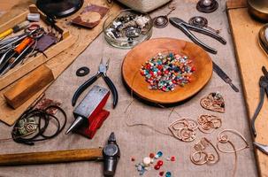 herramientas de trabajo de alambre de cobre hechas a mano sobre la mesa con accesorios. concepto de arte de personas de artesanía foto