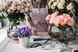 A florist writes in a craft notebook in a store among the flowers. photo