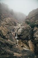 Crimean mountain river among rocks and stones. Waterfall in fog. photo