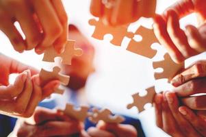 Close-up of a businessman with puzzle pieces in his hands arranged together. teamwork unity in teamwork The concept of combining physical strength and power at work. photo