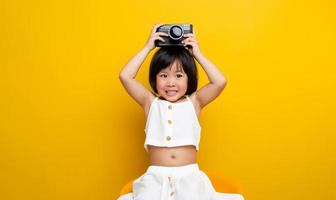 Asian female photographer taking a picture on a yellow background Has a cute smile like a childhood photo