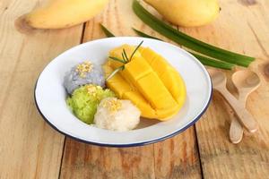 Thai famous delicious dessert - Closeup plate of sweet fresh ripe mango with three color of sticky rice , green from pandan and purple from butterfly pea flower photo