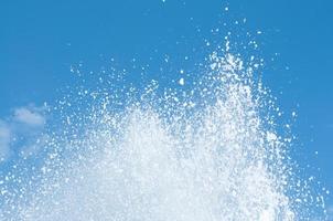 Cool and fresh water splashes on the clear blue sky background. photo