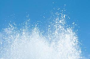 Cool and fresh water splashes on the clear blue sky background. photo