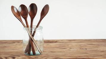 Wooden spoons in a glass jar on a wooden table photo