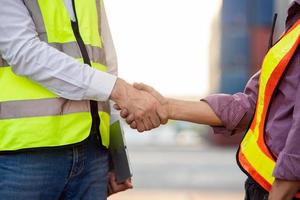 Businessman and engineers working successful handshake together into container for loading. Industrial and logistic concept photo