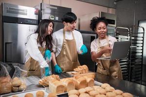 Three young friends and startup partners of bread dough and pastry foods busy with homemade baking jobs while cooking orders online, packing, and delivering on bakery shop, small business entrepreneur photo