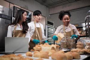 Three young friends and startup partners of bread dough and pastry foods busy with homemade baking jobs while cooking orders online, packing, and delivering on bakery shop, small business entrepreneur photo