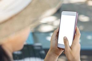 Close-up Asian woman hands holding and pointing on smartphone sunbathing by the sea. Online shopping, social, technology, communication. Clipping path on white screen isolated photo