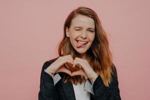 Happy excited young woman showing heart shape sign photo