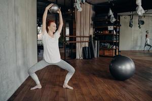 Sportive woman training with small pilates ball in half sitting position during ballet workout photo