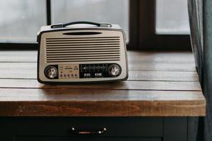 radio vintage retro en la superficie de la mesa de madera cerca de la ventana. volver a los 80 nostalgia musical y concepto de tecnología antigua. grabadora antigua