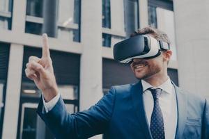 Smiling bearded businessman with stubble wearing VR glasses, viewing something in virtual reality photo