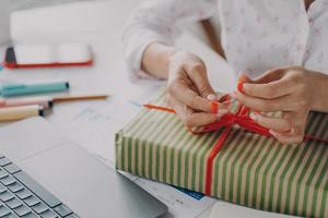 manos femeninas paquete de embalaje caja de regalo para el cliente durante las vacaciones de invierno de navidad foto