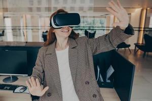 mujer tratando de esquivar algo en realidad virtual mientras trabaja en la oficina foto