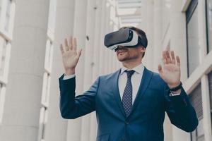 Businessman using VR headset for virtual reality game for work, standing outdoors photo