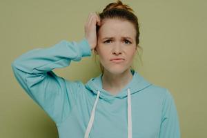 Young confused brunette woman in blue hoodie photo