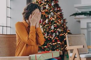 Curious woman covering eyes with hands and guessing what inside of Christmas gift box photo