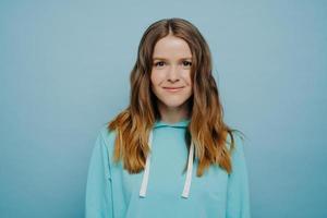 Portrait of teenage girl smiling at camera posing isolated over blue background photo