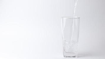 versando la bevanda di acqua fresca nel bicchiere su sfondo grigio. versando acqua video