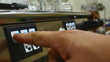 les mains d'une jeune femme barista appuyaient sur le bouton de démarrage de la machine à café video