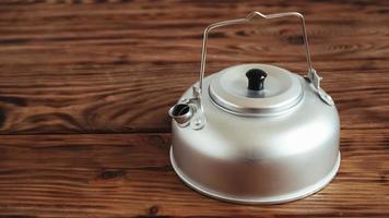 Metal kettle for hiking on a wooden table background photo