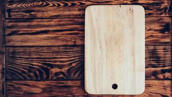 Wooden cutting board on brown table background photo