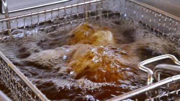 Fryer from the food net is lowered into boiling oil in an outdoor fast-food restaurant video
