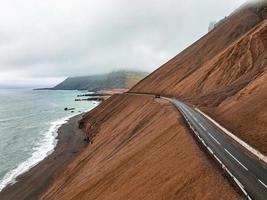 camino interminable hacia las montañas nubladas y las colinas de islandia durante el clima soleado y nublado. foto