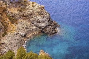 vista de ángulo alto de la formación rocosa en la costa mediterránea azul durante el día soleado foto