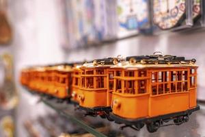 Close-up of orange tram souvenirs on shelf at shop for sale in town photo