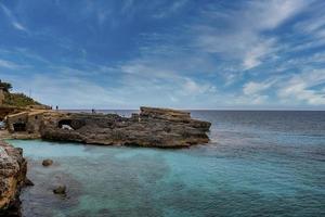 View of tourists exploring rocky cliff in scenic island against blue sky photo