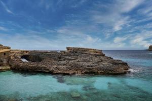 Idyllic view of rocky cliff on beautiful blue ocean in island against sky photo