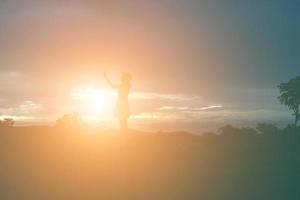 Silhouette of woman praying over beautiful sky background photo