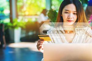 Young woman entering credit card number on laptop computer shopping online at home with infographics. Selected focus photo