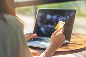 mujer joven ingresando el número de tarjeta de crédito en la computadora portátil comprando en línea en casa. foco seleccionado foto