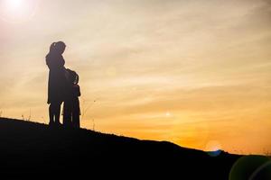 Mother encouraged her daughter out of the shadows at sunset. photo