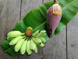 plátano crudo verde y flor de plátano en el fondo de la mesa de madera marrón foto