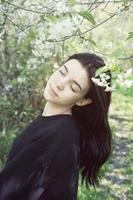 una linda adolescente está posando en el jardín cerca del manzano en flor con flores rosas. foto