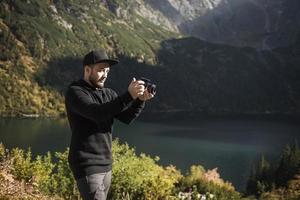 Young  man photographer taking photographs with digital camera in a mountains. photo