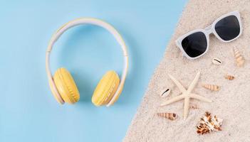 vista superior de auriculares inalámbricos y cámara, gafas de sol en sandalias con fondo azul. foto