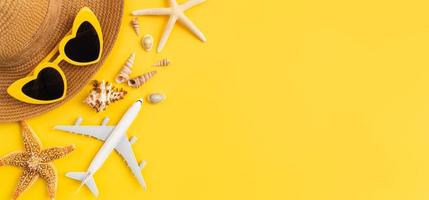 concepto de horario de verano, vista superior con espacio de copia de gafas de sol y sombrero con estrellas de mar sobre fondo amarillo. foto