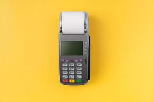 Card reader machine with invoice bill on yellow background. Online payment concept. photo