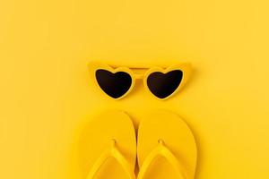 Summer time concept, top view with copy space of flip flops and sunglasses on yellow background. photo