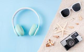 Top view of wireless headphones and camera, sunglasses on sandals with blue background. photo