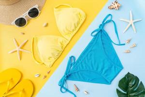 Top view of bikini and sunglasses with beach accessories on the yellow background. Summer time concept. photo