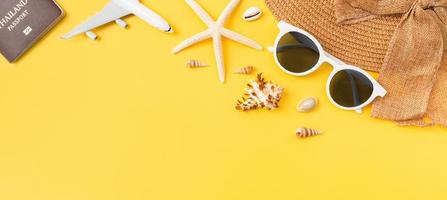 Top view with copy space of sunglasses and hat with starfish and airplane, passport on yellow background. photo