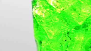 verter agua con gas verde con primeros planos de cubitos de hielo. video