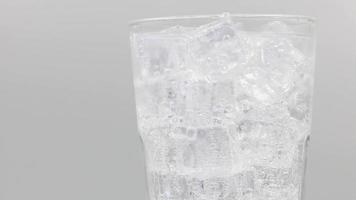 agua con gas de soda con hielo en vaso sobre fondo blanco. video