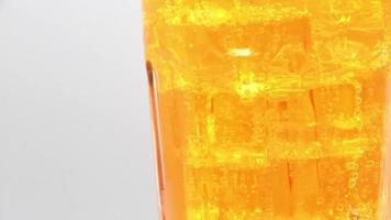 Rotate glass of Orange sparkling water drink over white background. video